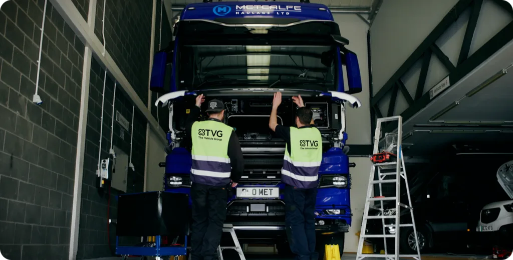 Wide angle shot of two TVG workers opening the hood on a truck